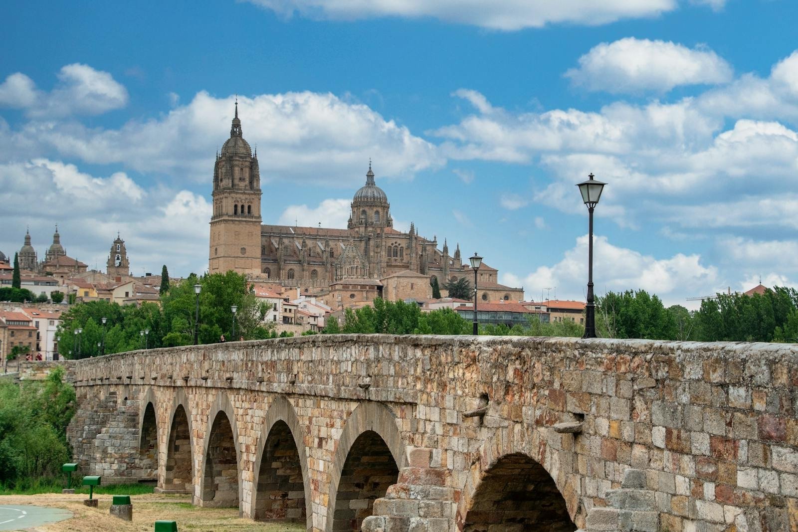 Stunning view of Salamanca Cathedral and the historic Roman Bridge under a blue sky.
