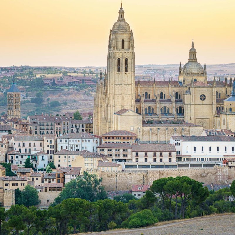 Panoramic view of Segovia Cathedral with a beautiful sunset backdrop, highlighting its architectural grandeur.